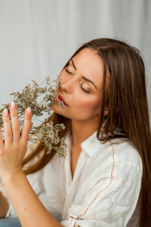 Portrait of beautiful young woman with long hair on white background with dried flowers.の写真素材