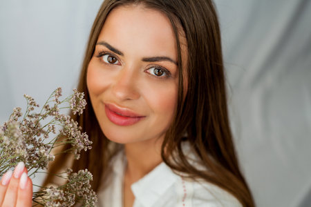 Portrait of beautiful young woman with long hair on white background with dried flowers.の写真素材