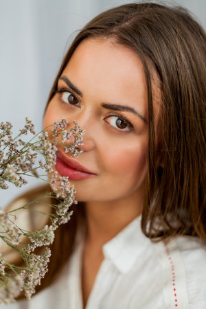 Portrait of beautiful young woman with long hair on white background with dried flowers.の写真素材