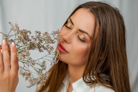 Portrait of beautiful young woman with long hair on white background with dried flowers.の写真素材
