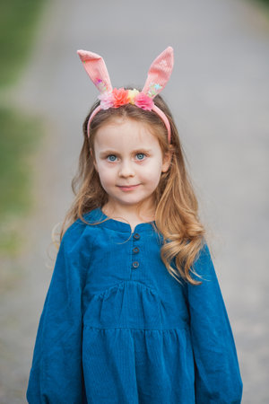 Easter. Little cute girl with long curly hair with bunny ears in cherry blossoms. Spring.の写真素材