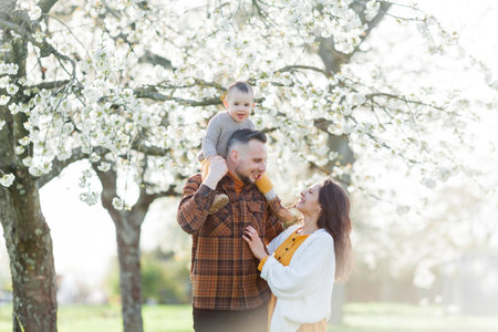 Happy young family with little son walks in blooming garden. Mom and dad with 1 year old baby.の写真素材