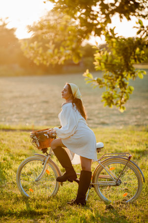 Beautiful young dark-haired woman on picnic in the field. Model in stylish clothes with bicycle.の写真素材