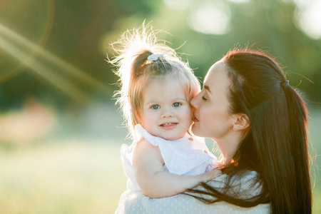 Beautiful young mother with little daughter on a picnic in the field. Summer breakfast with lemons.の写真素材
