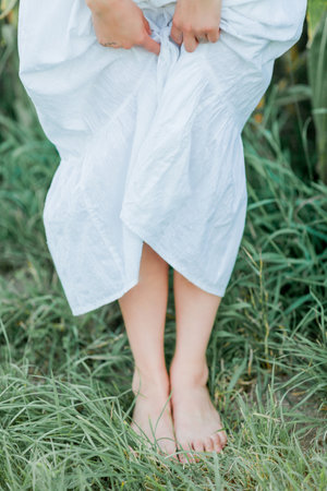 Young beautiful woman 26 years old in white simple dress in summer field. Green corn.の写真素材