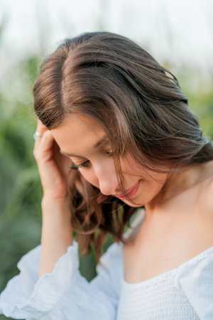 Young beautiful woman 26 years old in white simple dress in summer field. Green corn.の写真素材