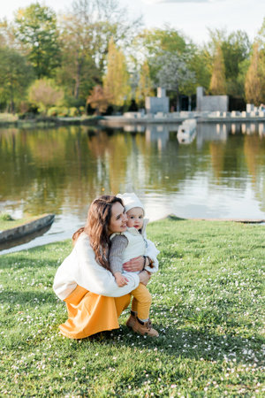 Young beautiful happy mother with her little son is walking in the park. Cozy autumn. Warm spring.の写真素材