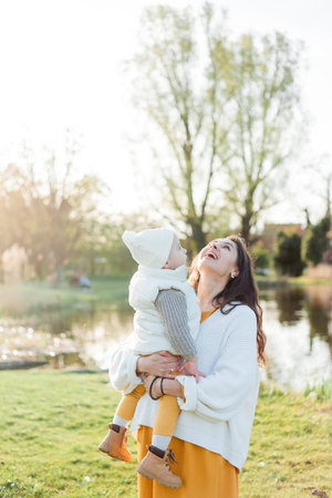Young beautiful happy mother with her little son is walking in the park. Cozy autumn. Warm spring.の写真素材