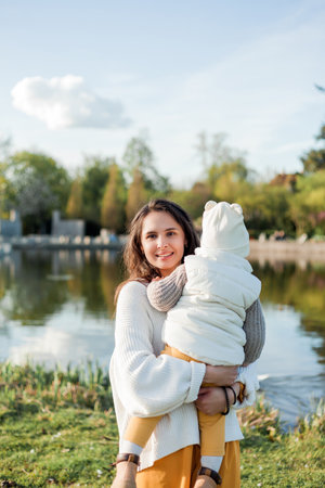 Young beautiful happy mother with her little son is walking in the park. Cozy autumn. Warm spring.の写真素材