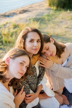 Young beautiful women of 25 years old on an autumn picnic near the lake. Glass of white wine, pastries. Happy models chatting merrily.の写真素材