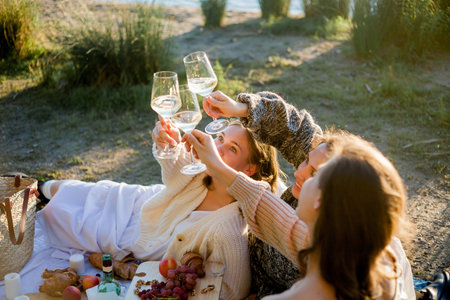 Young beautiful women of 25 years old on an autumn picnic near the lake. Glass of white wine,...