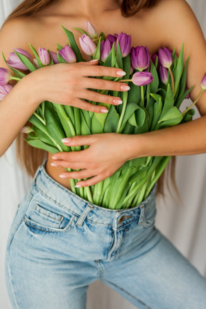 Beautiful young woman with long hair holds bouquet of tulips. Portrait of woman on white background. Spring holidays. Flowers.の写真素材