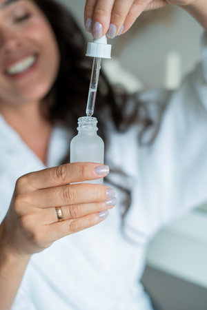 Young woman of 39 years applies rejuvenating serum to her face. Home spa.の写真素材