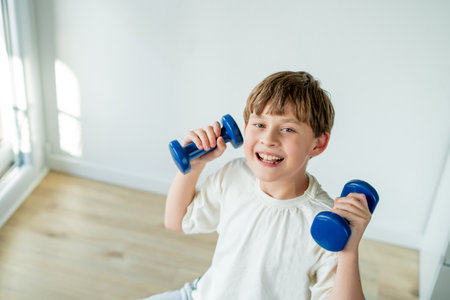 10 year old boy does sports with dumbbells and fitness ball at home. Home training.の写真素材