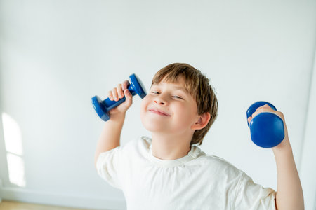 10 year old boy does sports with dumbbells and fitness ball at home. Home training.の写真素材