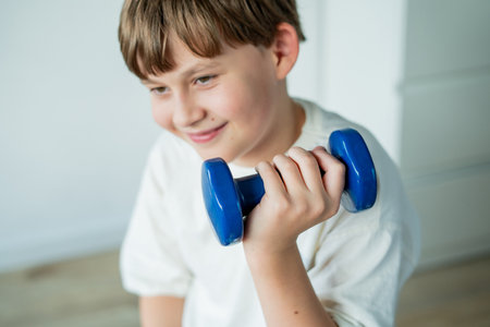 10 year old boy does sports with dumbbells and fitness ball at home. Home training.の写真素材
