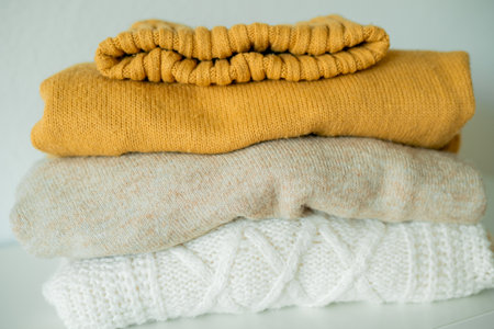 Warm cozy clothes on chest of drawers in home interior. Knitted autumn sweaters.の写真素材