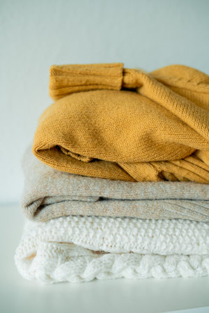 Warm cozy clothes on chest of drawers in home interior. Knitted autumn sweaters.の写真素材