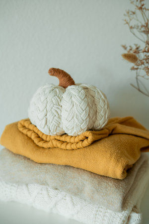 Knitted autumn sweaters on chest of drawers in home interior with pumpkins decor.の写真素材