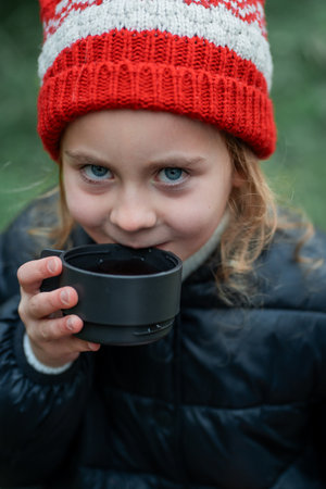 Cute little girl drinking hot tea. Holidays, picnic.の写真素材