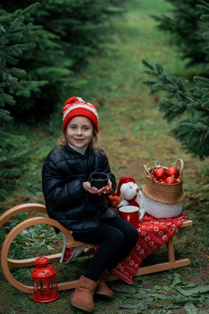 Cute little girl decorating Christmas tree in the forest. Holidays.の写真素材