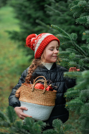 Cute little girl decorating Christmas tree in the forest. Holidays.の写真素材