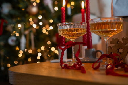 Glass glasses with champagne and red velvet ribbon near the Christmas tree. New Year. Winter holidays. Decor.の写真素材