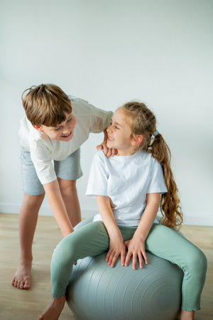 Little girl and boy doing sports at home with fitness ball.