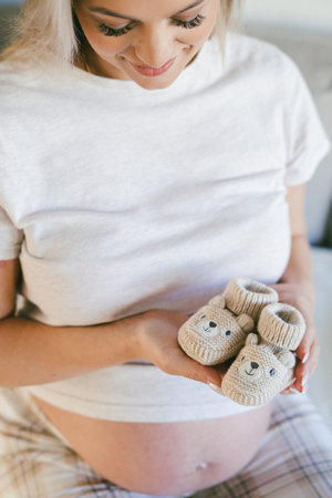 Young beautiful woman in pajamas is packing bag of baby things for the maternity ward. Model with belly is preparing to be mother.の写真素材