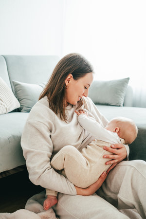 Happy mother breastfeeding her little baby in her arms at home.の写真素材