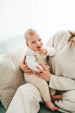 Happy mother holding her little son 9 months in her arms at home.