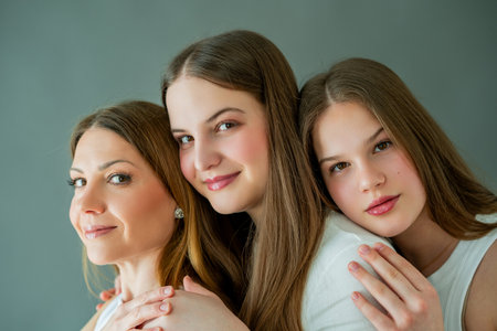 Two teenage daughters hugging their young mother at home. Happy mother and two girls exchanging...
