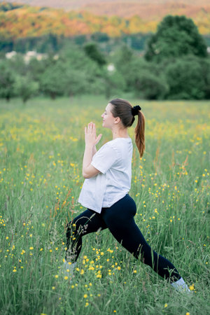 Pregnant young woman in sportswear doing yoga on the street outside the city. Therapeutic sports in the park. Motherhood. Meditation.の写真素材