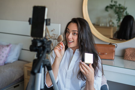Young woman doing her makeup in front of the camera for her video blog. Social media.の写真素材