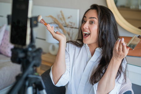 Young woman doing her makeup in front of the camera for her video blog. Social media.の写真素材