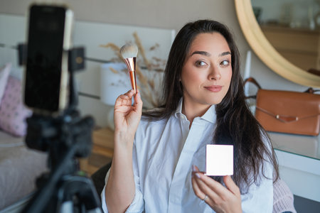Young woman doing her makeup in front of the camera for her video blog. Social media.の写真素材