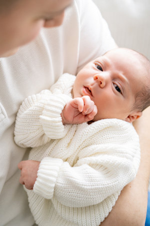 Close-up of a small newborn baby in the arms of his father. Dad hugs his little son. Cozy.の写真素材
