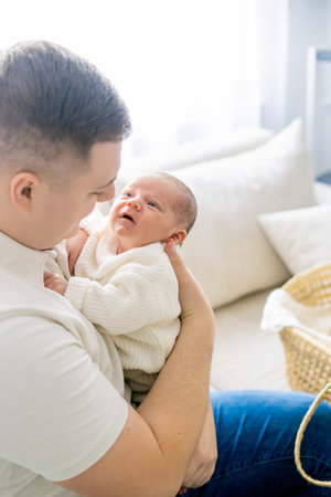 Close-up of a small newborn baby in the arms of his father. Dad hugs his little son. Cozy.の写真素材