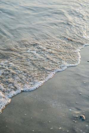 Closeup of the sea at sunset. Beach with sand. Blue water.