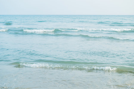 Closeup of the sea at sunset. Beach with sand. Blue water.