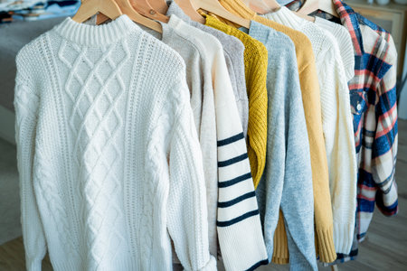 Warm cozy clothes on hangers. Knitted autumn sweaters. Organization.