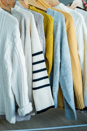 Warm cozy clothes on hangers. Knitted autumn sweaters. Organization.