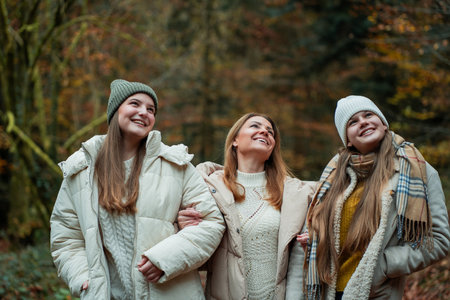 Young mother with her teenage daughters on a walk in the autumn forest.