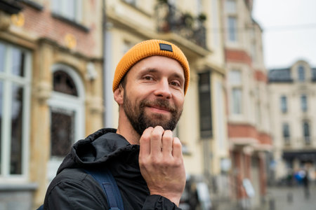 Portrait of man with a beard in autumn clothes. Tourist with a backpack in an old European city.
