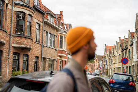 Portrait of man with a beard in autumn clothes. Tourist with a backpack in an old European city.