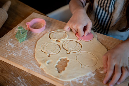 Little cute girl is making cookies in the kitchen. Cozy autumn.