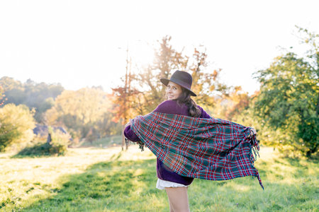 Autumn portrait of a young woman outdoors with a warm cozy blanket.の写真素材