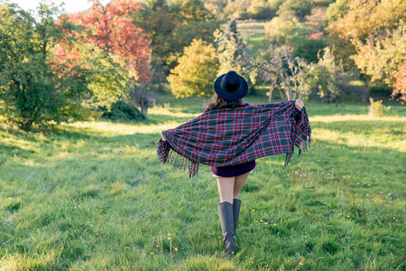 Autumn portrait of a young woman outdoors with a warm cozy blanket.の写真素材