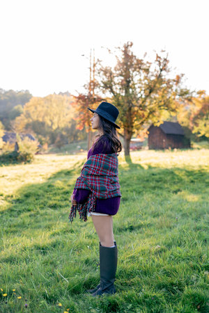 Autumn portrait of a young woman outdoors with a warm cozy blanket.