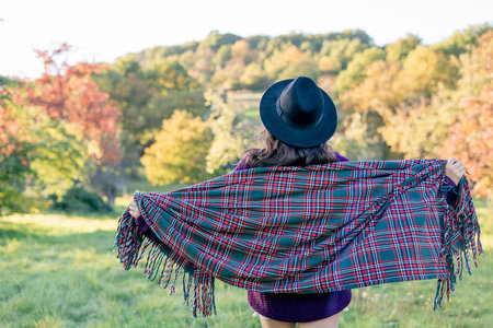 Autumn portrait of a young woman outdoors with a warm cozy blanket.の写真素材